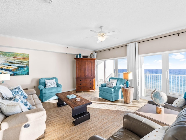 living room featuring ceiling fan, crown molding, a textured ceiling, and a water view