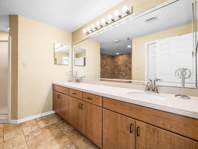 bathroom with a shower, vanity, and a textured ceiling