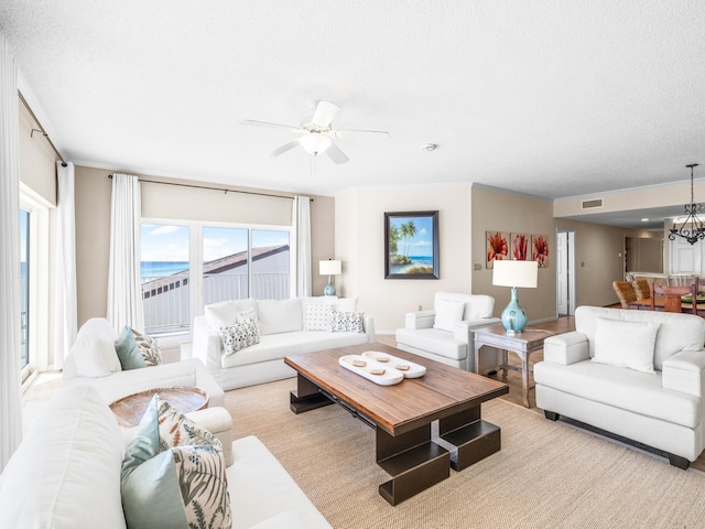 living area with visible vents, a textured ceiling, and ceiling fan with notable chandelier