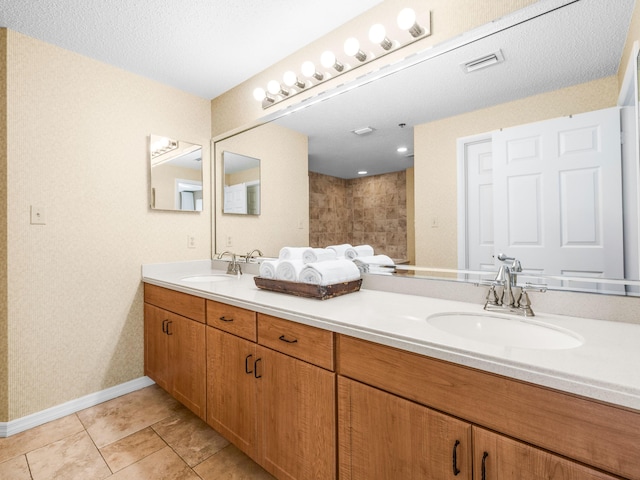 full bathroom with double vanity, baseboards, a walk in shower, and a sink