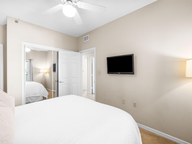 bedroom featuring a closet, light colored carpet, visible vents, a ceiling fan, and baseboards