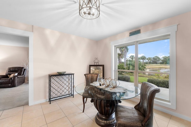 tiled dining room with a water view and an inviting chandelier