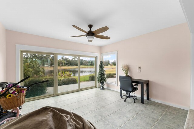 office space with ceiling fan, a water view, and light tile patterned floors