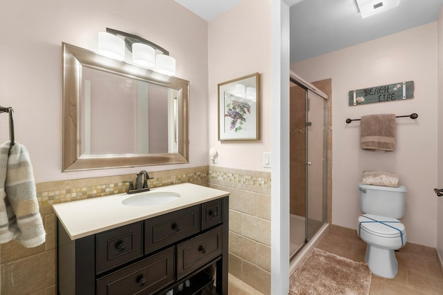 bathroom with tile patterned floors, vanity, toilet, and a shower with door