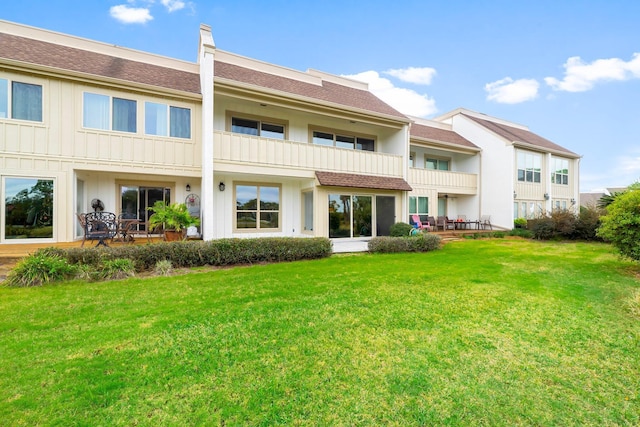 back of property with a yard and a balcony