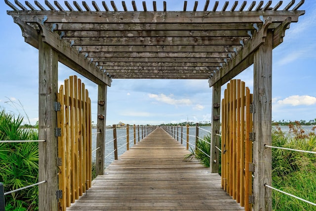 view of dock with a pergola and a water view