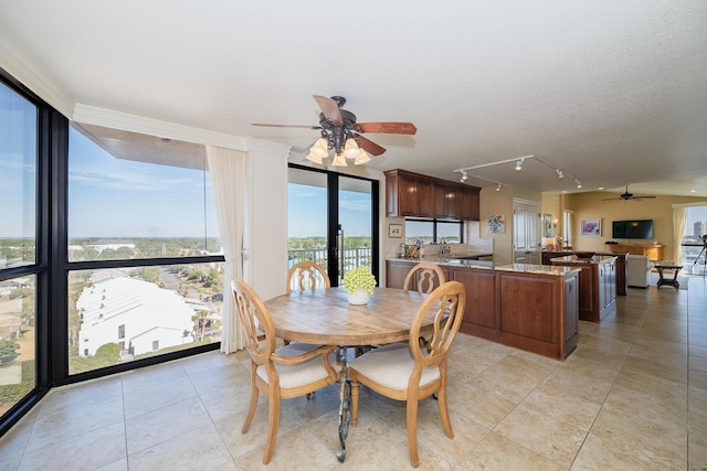 dining room featuring ceiling fan, a textured ceiling, light tile patterned flooring, expansive windows, and rail lighting