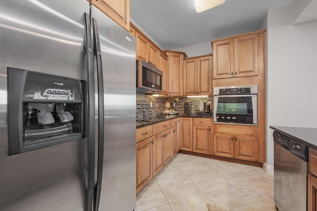 kitchen featuring appliances with stainless steel finishes, tasteful backsplash, dark stone counters, and light tile patterned flooring