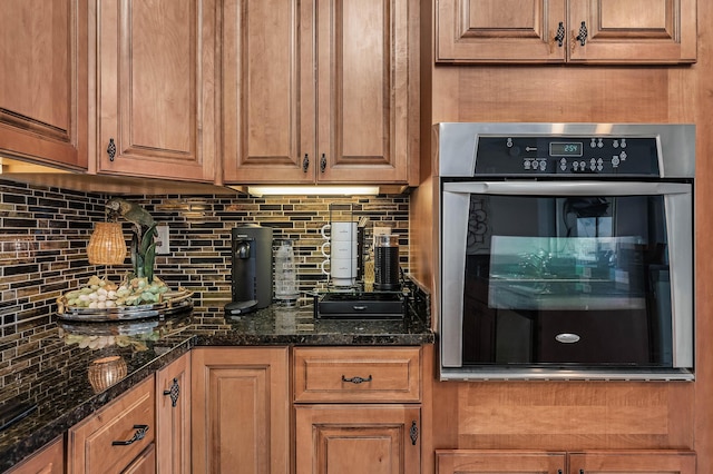 kitchen with backsplash, oven, and dark stone counters