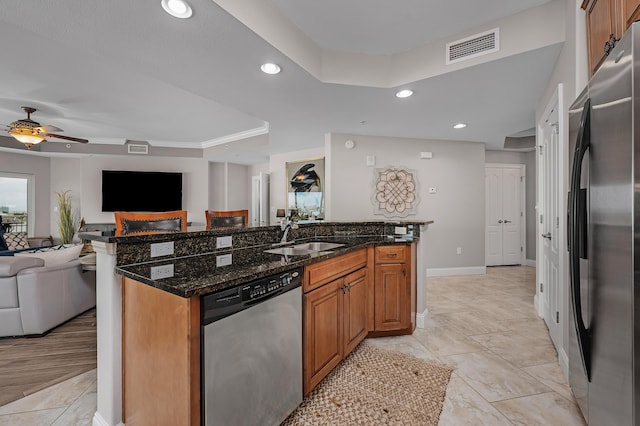 kitchen with a center island with sink, sink, appliances with stainless steel finishes, and dark stone counters