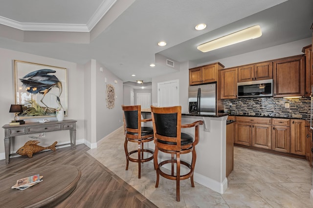 kitchen with backsplash, a kitchen breakfast bar, crown molding, a kitchen island, and stainless steel appliances