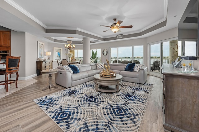 living room featuring ceiling fan with notable chandelier, a raised ceiling, and crown molding