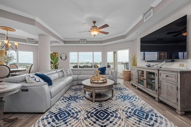 living room featuring crown molding, light hardwood / wood-style flooring, and a tray ceiling