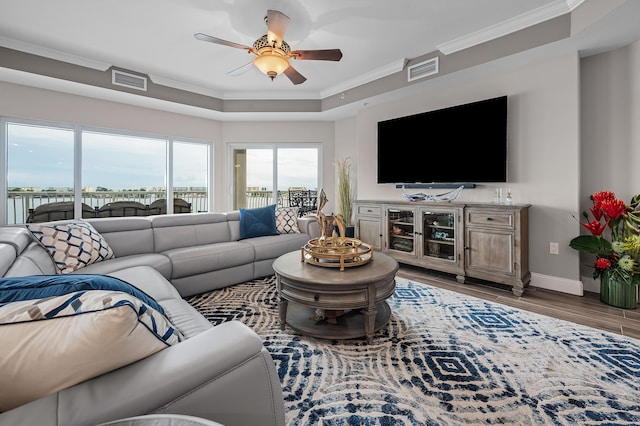 living room featuring hardwood / wood-style floors, a raised ceiling, ceiling fan, and crown molding