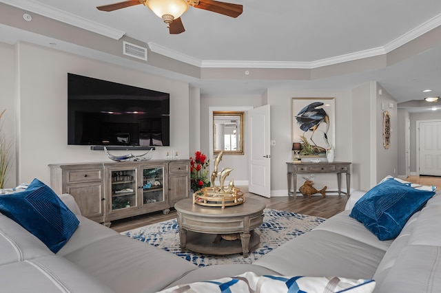 living room featuring a tray ceiling, crown molding, hardwood / wood-style floors, and ceiling fan