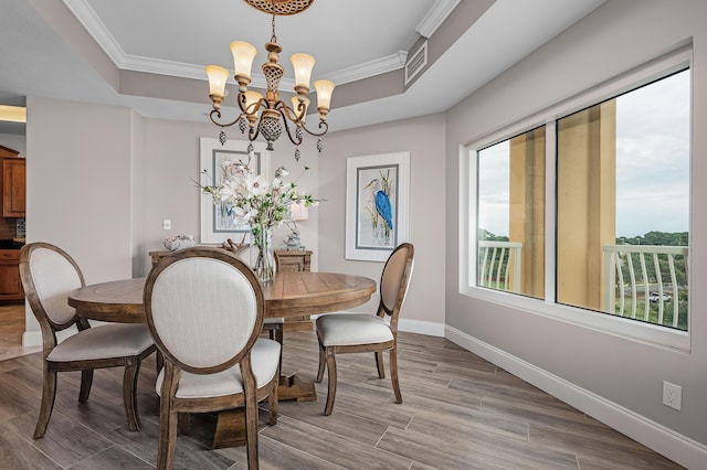 dining area with a healthy amount of sunlight, ornamental molding, a tray ceiling, and an inviting chandelier