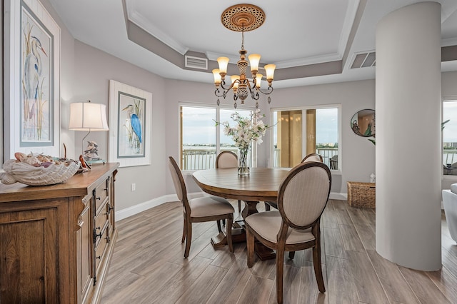 dining space featuring a tray ceiling, an inviting chandelier, and ornamental molding