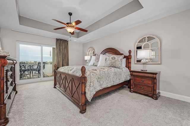 carpeted bedroom featuring a raised ceiling, access to exterior, and ceiling fan