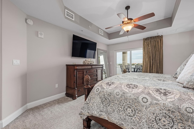 bedroom with a raised ceiling, ceiling fan, light carpet, and access to outside