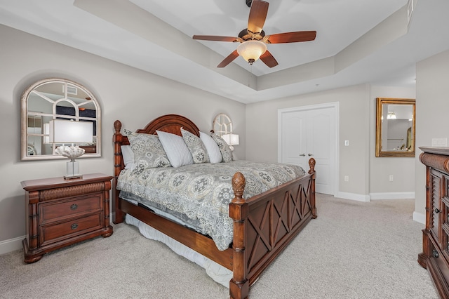 carpeted bedroom featuring a tray ceiling and ceiling fan