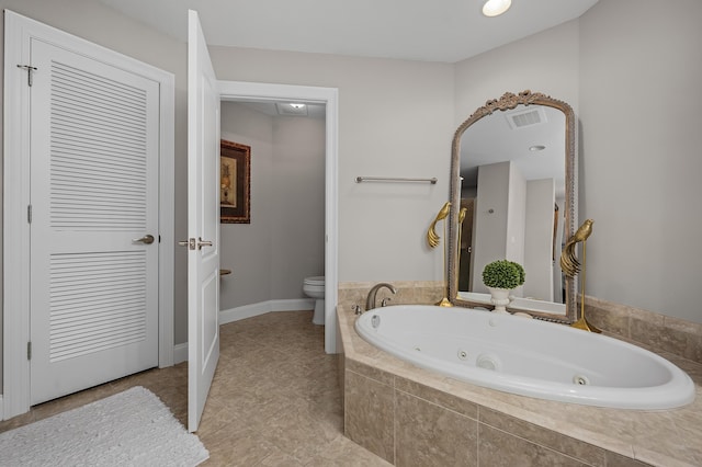 bathroom with tile patterned floors, toilet, and tiled bath