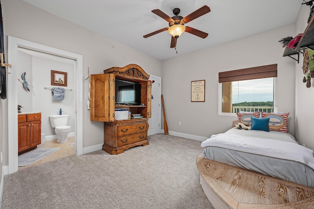 carpeted bedroom with ensuite bath and ceiling fan