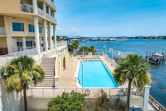 view of pool featuring a water view and a patio