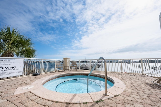 view of swimming pool featuring a water view and a hot tub