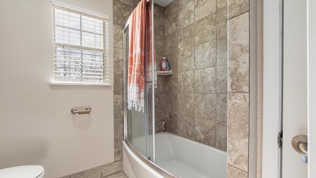 bathroom with shower / bath combination with glass door, a healthy amount of sunlight, and toilet