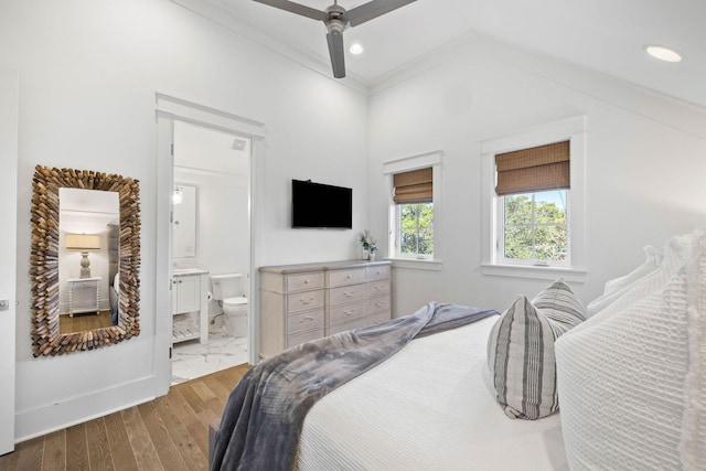 bedroom featuring light wood-type flooring, ensuite bathroom, ceiling fan, and ornamental molding