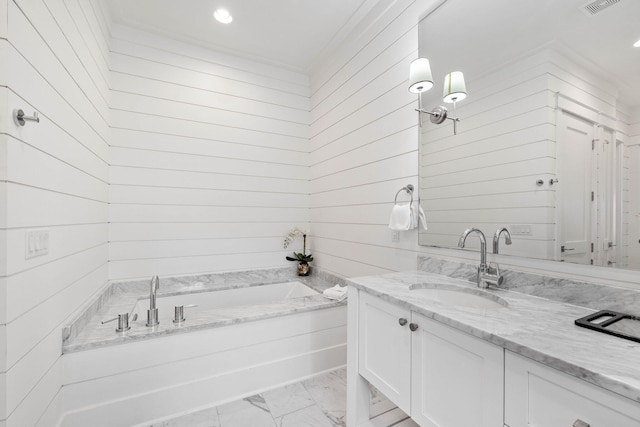 bathroom with a washtub, vanity, and wood walls