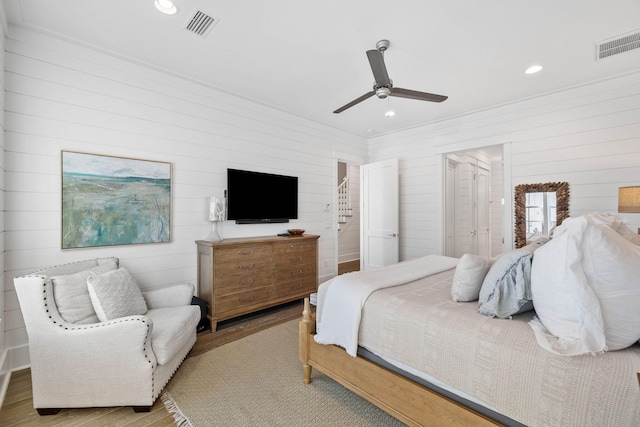 bedroom featuring light hardwood / wood-style floors, ceiling fan, and wood walls