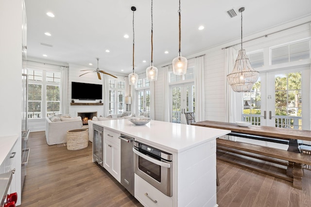 kitchen featuring french doors, a center island, decorative light fixtures, a fireplace, and white cabinets