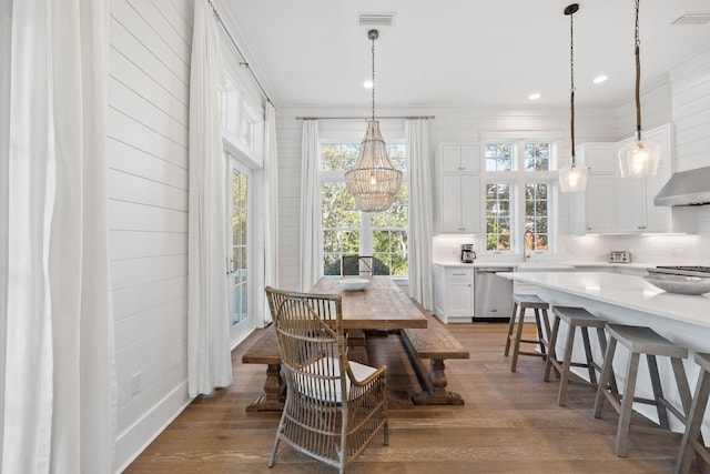 dining space with a healthy amount of sunlight, light wood-type flooring, and an inviting chandelier