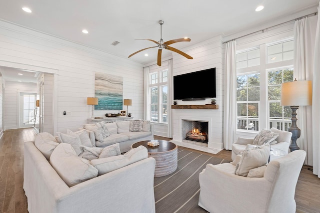 living room with a fireplace, a healthy amount of sunlight, ceiling fan, and dark wood-type flooring