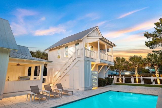 pool at dusk featuring ceiling fan and a patio area