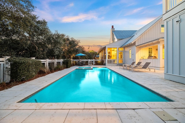 pool at dusk featuring a patio