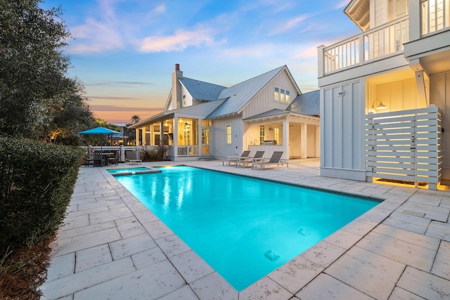 pool at dusk featuring a patio