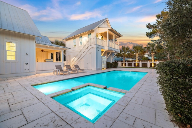 pool at dusk with an in ground hot tub, ceiling fan, and a patio area