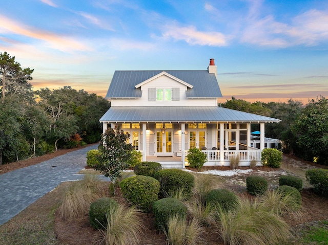 back house at dusk with a porch and french doors