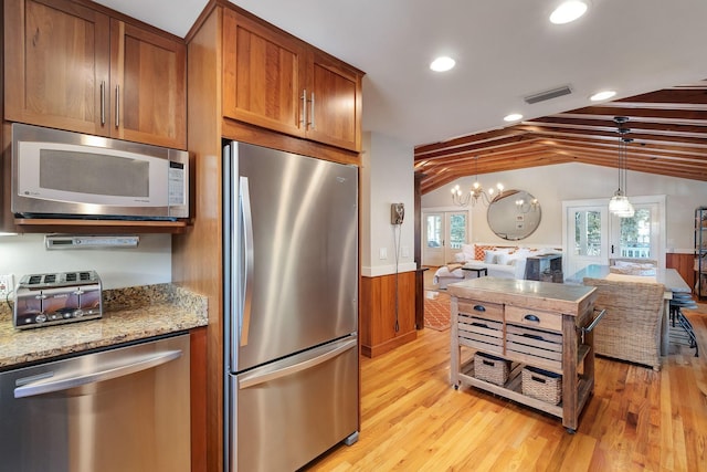 kitchen featuring french doors, lofted ceiling with beams, hanging light fixtures, wooden walls, and stainless steel appliances