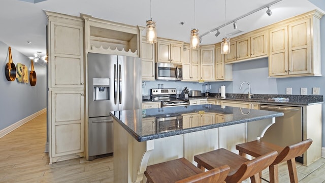 kitchen with appliances with stainless steel finishes, light hardwood / wood-style flooring, a kitchen island, and pendant lighting