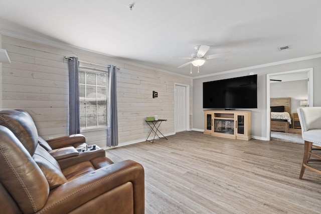 living room featuring ornamental molding, ceiling fan, light hardwood / wood-style flooring, and wood walls