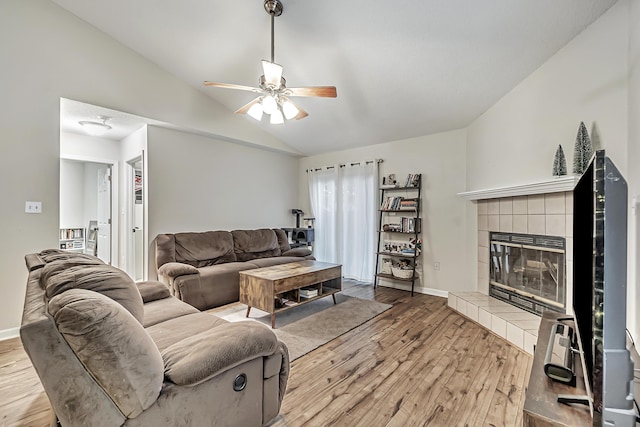 living room with ceiling fan, a fireplace, hardwood / wood-style floors, and lofted ceiling