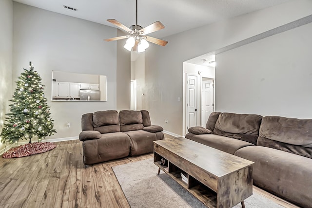 living room with light wood-type flooring, vaulted ceiling, and ceiling fan