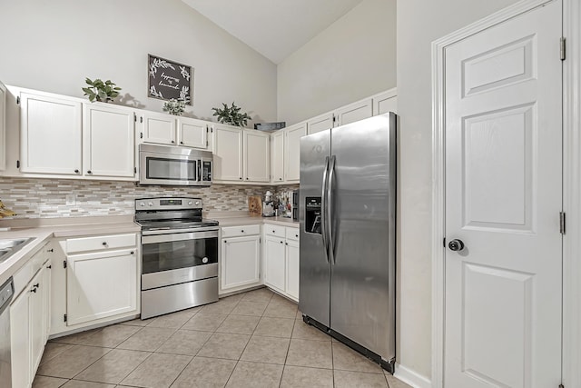 kitchen with high vaulted ceiling, white cabinets, light tile patterned floors, tasteful backsplash, and stainless steel appliances