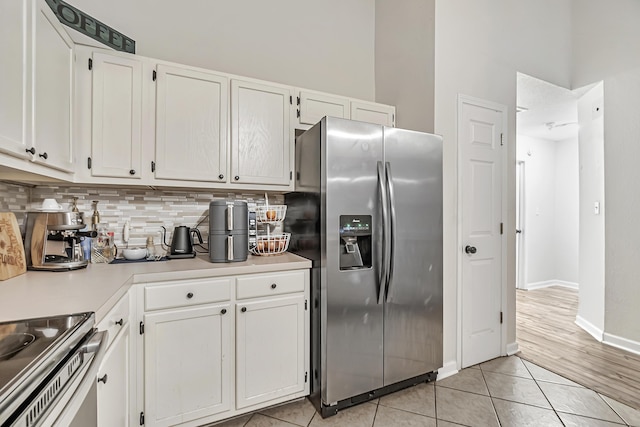 kitchen with backsplash, white cabinetry, light tile patterned flooring, and appliances with stainless steel finishes