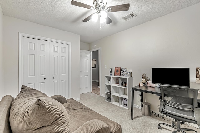 carpeted home office featuring a textured ceiling and ceiling fan