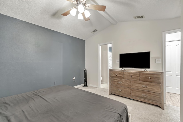 carpeted bedroom with vaulted ceiling with beams, ceiling fan, ensuite bathroom, and a textured ceiling