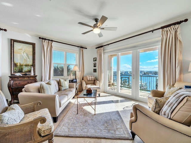 living room with ceiling fan, a water view, and crown molding